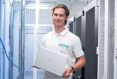 Lehrling IT Junger Mann mit Laptop in der Hand im Serverraum